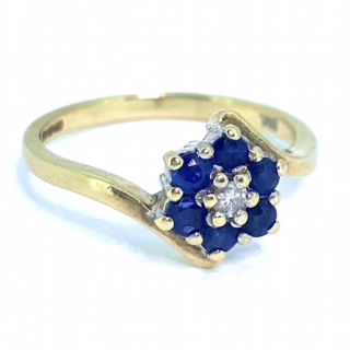 A Vintage Diamond and Sapphire Cross Over Cluster Ring, hallmarked 9ct. Six royal blue sapphires, surround the central diamond, all claw set.