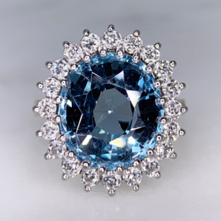 Aquamarine and Diamond Cluster Ring, 18ct Gold Hallmarked. The principle faceted Aquamarine and surrounding diamonds are claw set in a tiffany shank. The head of the ring measures approximately 18mm x 21mm.