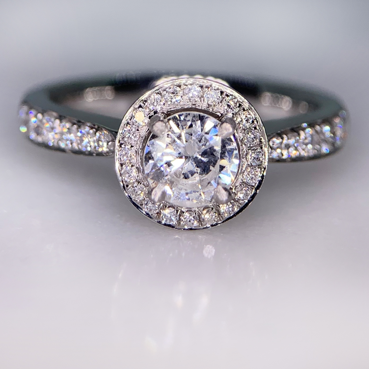 Incredible Diamond Halo Cluster Ring in 950 Platinum. The exquisite halo ring has a 0.63carat centre diamond, claw set with diamond halo. The head of the ring measures 9 mm in diameter with 12 diamond embellished shoulders. The ring has a flat sided-court shank, polished. All the stones are claw set. The ring is in absolutely immaculate condition.