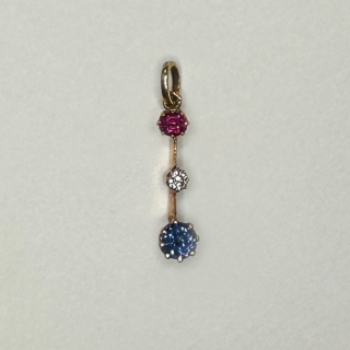 Exquisite fine Edwardian three stone gem pendant with colours red, white and blue. The pendant is set in a 15ct yellow gold. The ruby on top followed by a smaller brilliant cut antique diamond, the sapphire to the bottom of the pendant. The gems have claw settings. The drop including the bale is 2.5cm. 