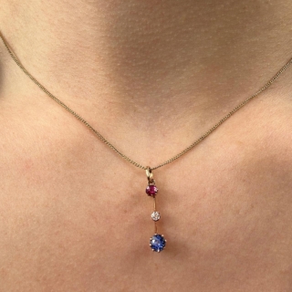 Exquisite fine Edwardian three stone gem pendant with colours red, white and blue. The pendant is set in a 15ct yellow gold. The ruby on top followed by a smaller brilliant cut antique diamond, the sapphire to the bottom of the pendant. The gems have claw settings. The drop including the bale is 2.5cm. 