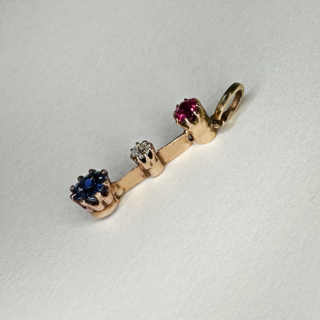 Exquisite fine Edwardian three stone gem pendant with colours red, white and blue. The pendant is set in a 15ct yellow gold. The ruby on top followed by a smaller brilliant cut antique diamond, the sapphire to the bottom of the pendant. The gems have claw settings. The drop including the bale is 2.5cm. 