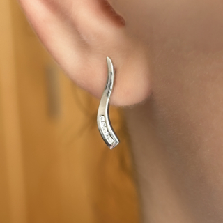 White Gold & Diamond Wave Earrings.  A sleek and contemporary pair of diamond earrings crafted in polished 9ct white gold, designed in an elegant flowing wave form and set with 5 sparkling round diamonds. The softly curved silhouette gives these earrings a refined, sculptural appearance, while the channel-set diamonds add a delicate line of light and brilliance. Their clean modern design makes them exceptionally versatile — ideal for both everyday wear and evening styling. From the post to the bottom the earrings measure 1.3cm, the total length is 1.7cm. On the back of the earrings there is a 9ct '375' stamp as well as a diamond stamp 'DIA 0.1' Please contact us if you would like to know more about these gorgeous earrings or visit us at Saddingtons Jewellery, Mayfair.