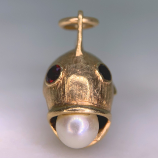 Characterful Vintage Garnet and Pearl in Mouth Fish Charm in 9ct Rose Gold, Hallmarked London, 1965. This wonderful charm has two deep garnet eyes, bezel set, measuring approximately 3 mm in diameter. The fish holds a fresh water pearl 6 mm in diameter in an open mouth. The fish is designed with intricate fin and scale chased detail. The total fish measures 31 mm x 22 mm (excluding the 7 mm loop). The charm is in excellent condition and a perfect quirky addition to any charm bracelet or necklace.