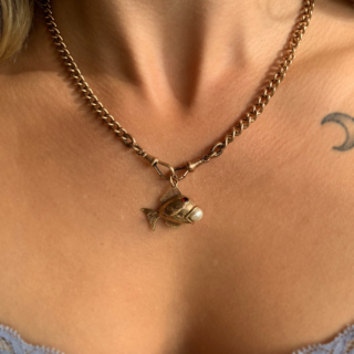 Characterful Vintage Garnet and Pearl in Mouth Fish Charm in 9ct Rose Gold, Hallmarked London, 1965. This wonderful charm has two deep garnet eyes, bezel set, measuring approximately 3 mm in diameter. The fish holds a fresh water pearl 6 mm in diameter in an open mouth. The fish is designed with intricate fin and scale chased detail. The total fish measures 31 mm x 22 mm (excluding the 7 mm loop). The charm is in excellent condition and a perfect quirky addition to any charm bracelet or necklace.