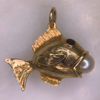 Characterful Vintage Garnet and Pearl in Mouth Fish Charm in 9ct Rose Gold, Hallmarked London, 1965. This wonderful charm has two deep garnet eyes, bezel set, measuring approximately 3 mm in diameter. The fish holds a fresh water pearl 6 mm in diameter in an open mouth. The fish is designed with intricate fin and scale chased detail. The total fish measures 31 mm x 22 mm (excluding the 7 mm loop). The charm is in excellent condition and a perfect quirky addition to any charm bracelet or necklace.