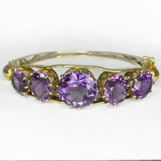 Antique Amethyst 5 Stone Gold Bangle.The top of this beautiful 5 graduating circular faceted amethysts,claw set within a galleried mount in polished yellow gold.The mounted amethysts are also set within 2 bands of gold with a gold sphere at each end.The bangle is hinged with a good strong hinge,there is a robust snap plate securing clasp with an additional figure of eight and ball securing clasp.The underside aspect of the bangle has graduating outer gold bands with ornate scrolling gold between the bands.A really beautiful bangle.The bangle is slightly oval allowing it to sit easily and comfortable on the wrist measuring 5.5 x 5.7 cm.Please contact us if you would like to know more about this bangle.