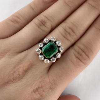 Stunning Victorian Emerald & Diamond Cluster Ring. This ring features a central rectangular natural emerald surrounded by 10 old cut diamonds. The ring mount is carved and the stones are all set closed back in 18ct yellow gold which is very typical of the era. The head of the ring measures at 1.8cm x 1.6cm. Please contact us if you would like to know more about this stunning ring or visit us at Saddingtons Jewellery, Mayfair.