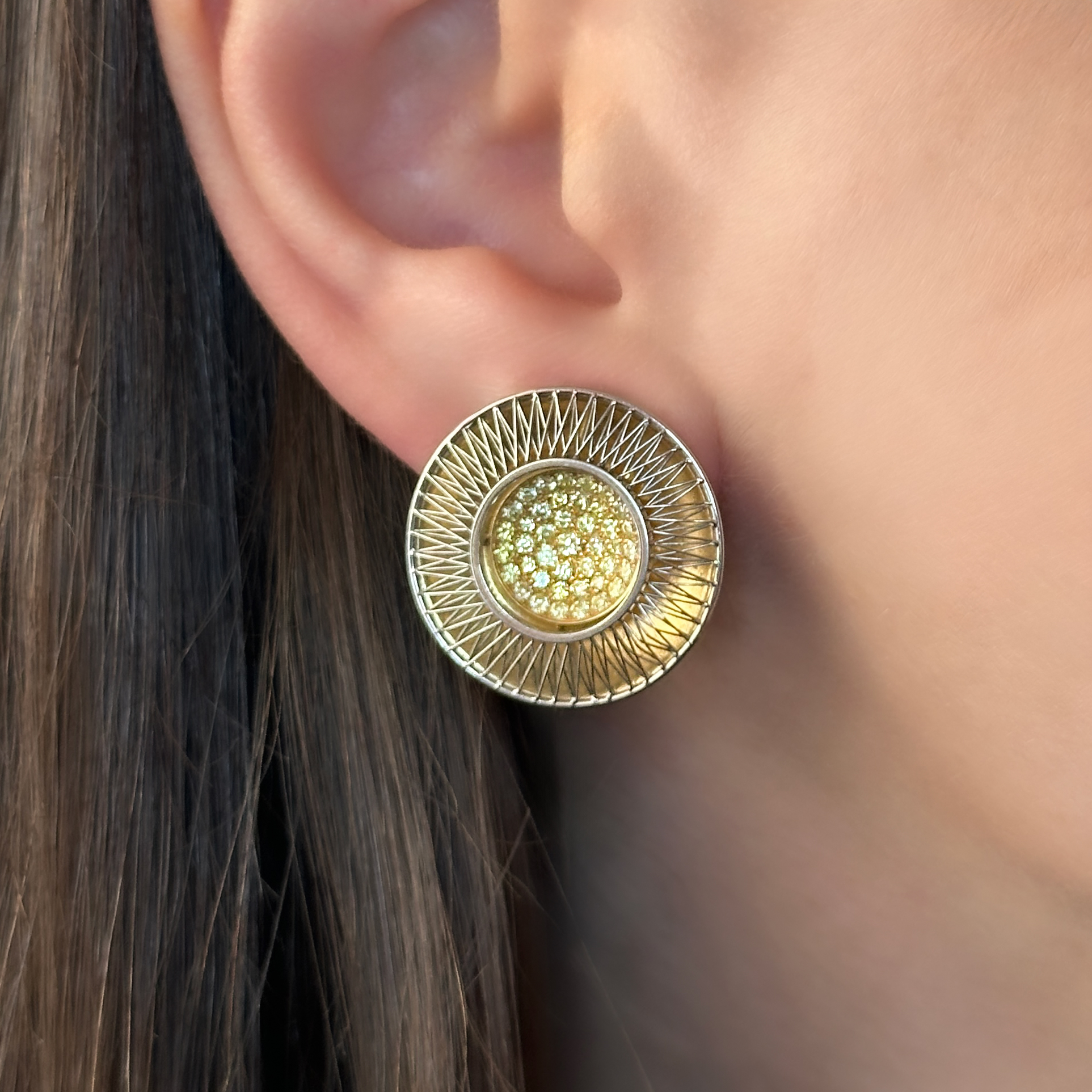 Striking Designer Tom Rucker Sun Stroke Earrings. Tom Rucker a multi award winning jewellery designer, he was awarded a Goldsmiths' Craft and Design Council Award for his innovative design Sun Stroke earrings. He is known for his unique techniques in working with lasering platinum wire. The circular Sun Stroke earrings measure 2.3cm in diameter, the centre of the earrings are set with fancy yellow diamonds measuring 1cm in diameter. The diamonds are set in polished 18ct yellow gold in a 'dish' shape with beautifully lasered criss crossing geometric wires of platinum. The earrings are secured on the ear by a 18ct gold post and D clip. The hallmark and makers mark are on the bottom of the earring clip denoting 'TR 750' with the London assay mark also. This is Tom Ruckers makers mark. The earrings will be displayed at Saddingtons Mayfair. Please contact us if you would like to know more about these extraordinary designer earrings or contact us at Saddingtons Mayfair to book a private client appointment. Price on enquiring.