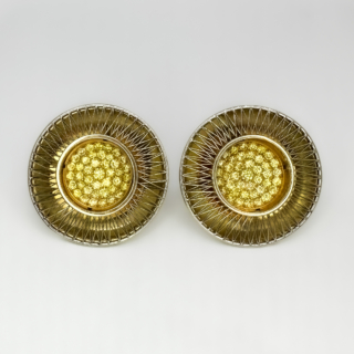 Striking Designer Tom Rucker Sun Stroke Earrings. Tom Rucker a multi award winning jewellery designer, he was awarded a Goldsmiths' Craft and Design Council Award for his innovative design Sun Stroke earrings. He is known for his unique techniques in working with lasering platinum wire. The circular Sun Stroke earrings measure 2.3cm in diameter, the centre of the earrings are set with fancy yellow diamonds measuring 1cm in diameter. The diamonds are set in polished 18ct yellow gold in a 'dish' shape with beautifully lasered criss crossing geometric wires of platinum. The earrings are secured on the ear by a 18ct gold post and D clip. The hallmark and makers mark are on the bottom of the earring clip denoting 'TR 750' with the London assay mark also. This is Tom Ruckers makers mark. The earrings will be displayed at Saddingtons Mayfair. Please contact us if you would like to know more about these extraordinary designer earrings or contact us at Saddingtons Mayfair to book a private client appointment.