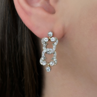 Unique, Beautiful Antique Diamond Rub Over Drop Earrings. Set with 6 small rub over Edwardian cut sparkling diamonds. The rub over diamonds are set in 3's in a scroll or clover shaped mount which are intertwined to form the drop. There are graine set smaller diamonds surrounding the rubover set diamonds. The earring fixing is a stud rub over diamond with is linked to the drop earring, the intertwining mount joins in the middle with a further rub over drop diamond at the bottom of the earring. The entire effect of articulated movement of the drop earrings creating a beautiful exquisite sparkling shimmer, perfect for evening wear. The back of the earrings are in 18ct yellow gold with the diamonds set in silver which is typical of the era. The earring drop measures 2.5cm from the diamond stud on the ear. The stud fixing has 18ct yellow gold butterfly securing fastener. Please contact us if you would like to know more about these earrings or visit us at Saddingtons Jewellery, Mayfair