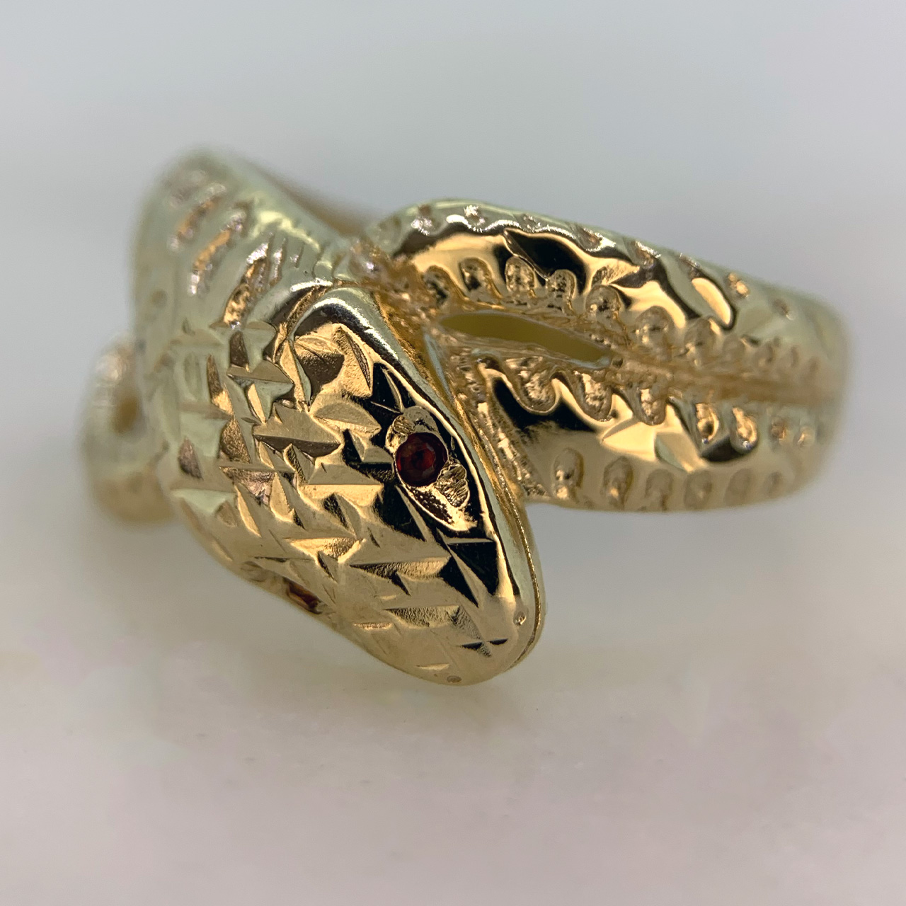 Beautiful Vintage Ruby Set and Diamond Cut Snake Ring in Hallmarked 9ct yellow Gold, Birmingham. The ring is embellished with two red ruby eyes measuring approximately 1.2 mm in diameter. The front of the shank is decorated with diamond cut detail to replicate a snakes scales, the shank tapers to the back where it is smooth polished. The width of the band is approximately 12.5 mm at the head and 2.5 mm at the back. These rings were extremely popular in the victorian era as they are a symbol of eternal love, this vintage retake of the ring is in excellent condition.