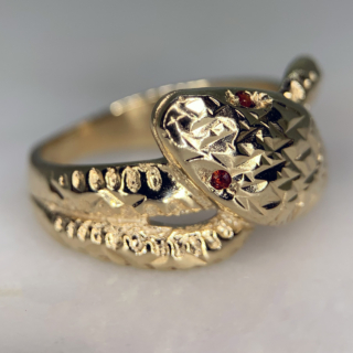 Beautiful Vintage Ruby Set and Diamond Cut Snake Ring in Hallmarked 9ct yellow Gold, Birmingham. The ring is embellished with two red ruby eyes measuring approximately 1.2 mm in diameter. The front of the shank is decorated with diamond cut detail to replicate a snakes scales, the shank tapers to the back where it is smooth polished. The width of the band is approximately 12.5 mm at the head and 2.5 mm at the back. These rings were extremely popular in the victorian era as they are a symbol of eternal love, this vintage retake of the ring is in excellent condition.