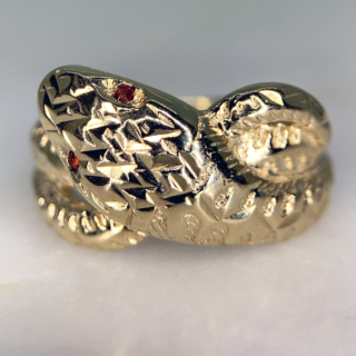Beautiful Vintage Ruby Set and Diamond Cut Snake Ring in Hallmarked 9ct yellow Gold, Birmingham. The ring is embellished with two red ruby eyes measuring approximately 1.2 mm in diameter. The front of the shank is decorated with diamond cut detail to replicate a snakes scales, the shank tapers to the back where it is smooth polished. The width of the band is approximately 12.5 mm at the head and 2.5 mm at the back. These rings were extremely popular in the victorian era as they are a symbol of eternal love, this vintage retake of the ring is in excellent condition.