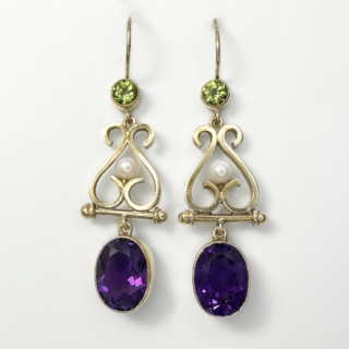 Pretty and Articulated Antique Suffragette Style Drop Earrings. 15ct yellow gold drop earrings with a rub over set peridot at the top of the earring leading to an articulated scrolled drop with a central pearl with the final articulated rub over oval amethyst drop. The earrings have a large kidney ear wire fitting, the total drop from the wire is 4 cm.  The articulated earrings sway beautifully when worn. Please contact us if you would like to know more about the earrings or visit us at Saddingtons Jewellery, Mayfair.