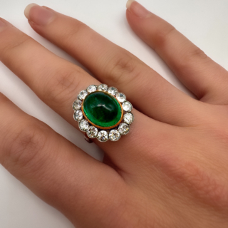 Rare and Beautiful Antique Large Cabochon Emerald Cluster Ring.This large columbian emerald ring is set in 18ct yellow gold and platinum shank.The central 6ct cabochon emerald is surrounded by 14 antique diamonds set in platinum and is graine set.Please contact us if you would like to know more about this ring.