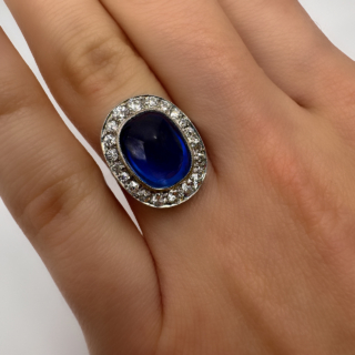 5.5ct Art Deco Burma Sapphire Cabochon Diamond Ring.Exquisite Burma sapphire cabochon diamond cluster ring.The central sapphire is certificated no heat.Surrounded by bright antique diamonds, set in platinum and all gems are graine set.This stunning ring is comfortable to wear and sits low on the finger.Please contact us if you would like to know more about this stunning ring.