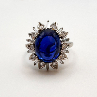 Cabochon Ceylon Sapphire Diamond Ring.Large cabochon royal blue claw set Ceylon sapphire which has gem certification,6ct weight.Stunning design with diamonds inside 'flower' petals with baguette diamond spacers.A real statement ring.A simple yet unique design.The shank is platinum with smooth curves on the mount.Please contact us if you would like to know more about this outstanding ring.