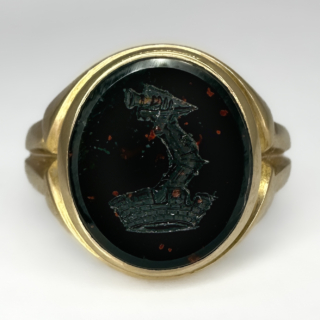 15ct Antique Bloodstone Heraldic Intaglio Signet Ring. An unusual heraldic intaglio depicting an armoured arm holding a dagger raising through a crown. The carved ring shank is in glowing 15ct gold, the bloodstone is dark with red and green hues. The Birmingham 15ct hallmark inside the ring shank. Please contact us if you would like to know more about this striking ring.
