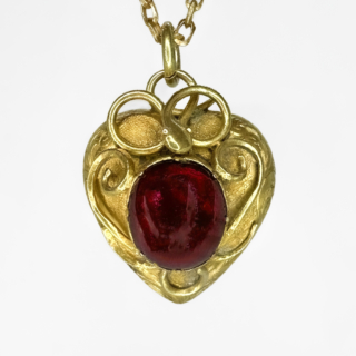 Delightful Victorian Cabochon Garnet Heart Pendant. 15ct glowing yellow gold wire work scrolls and writhing snake on the front and top of the locket. The back and the front of the locket has beautiful engraved scrolls adding intricate detail. The juicy cabochon garnet (0.8 x 0.8mm) is centrally set. Measuring 1.8 x 2cm with the bale. 